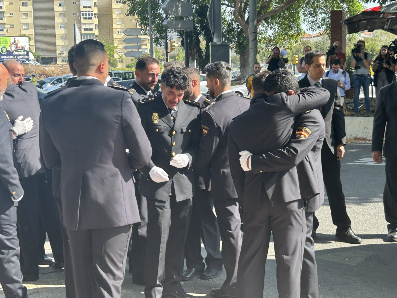 Compañeros del grupo 'Gotham', se abrazan tras introducir el féretro en el coche fúnebre