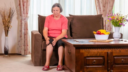Mujer mayor que sufre de dolor de rodilla en casa